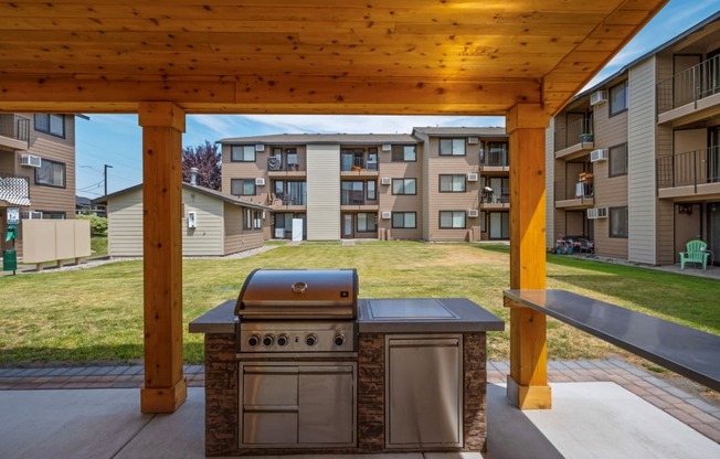 a barbecue grill is under a wooden pavilion surrounded by green grass. at Brix, Walla Walla