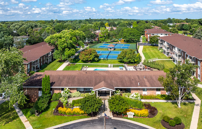 A large building with a pool in the middle of a green lawn.