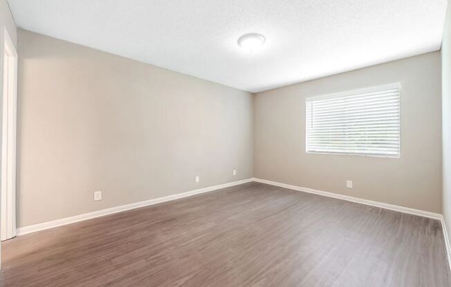 an empty living room with a window and wooden floors