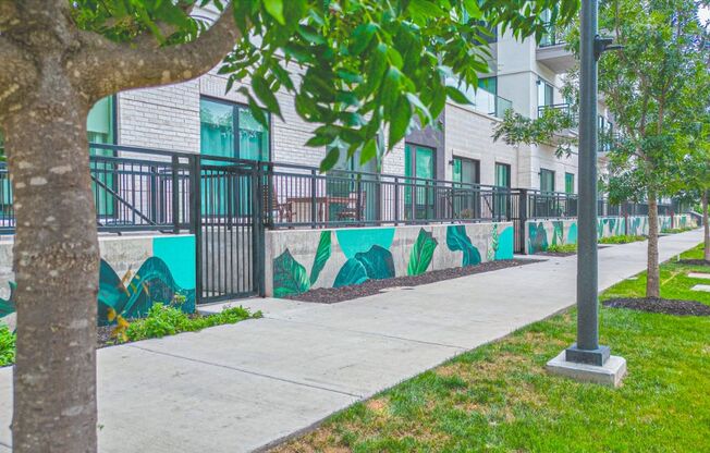 a sidewalk with a mural on the side of a building