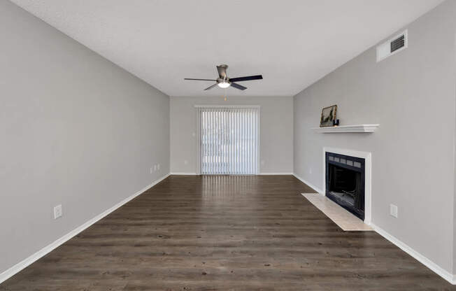 A spacious living room with a fireplace and a ceiling fan.