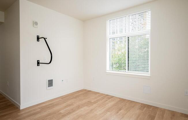 an empty room with a large window and wooden floors