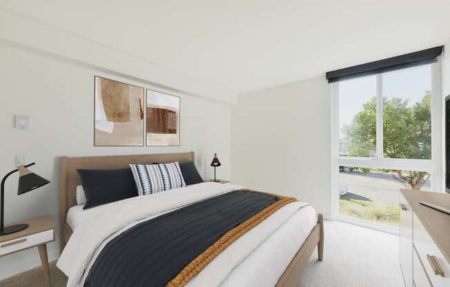 A bedroom with a large bed and a window overlooking a green area.