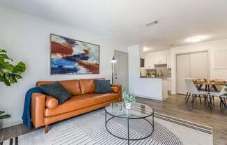 A living room with a brown leather couch and a painting on the wall.