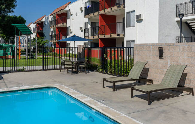 the pool area of California Villages Pico Rivera with chairs and a swimming pool