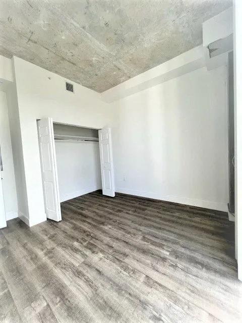 an empty room with white walls and wood floors