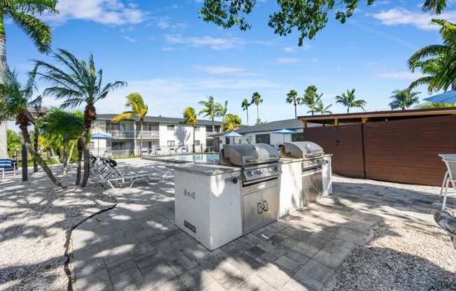 a patio with two grills and palm trees