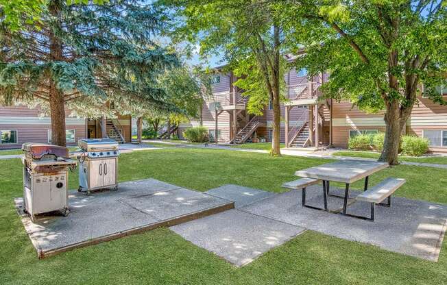 a picnic area with a grill and picnic table in front of a house