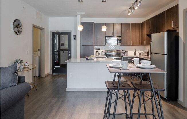 Centro Apartments model kitchen with table, track lights and brown cabinets