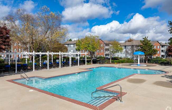 A large swimming pool surrounded by a white fence and trees.