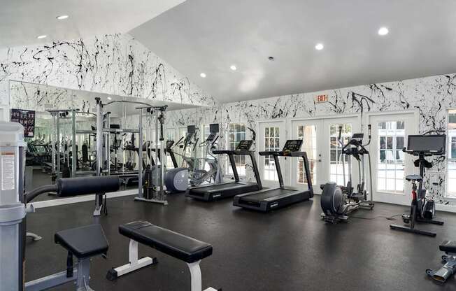A gym with a variety of equipment including treadmills, weights, and exercise machines.