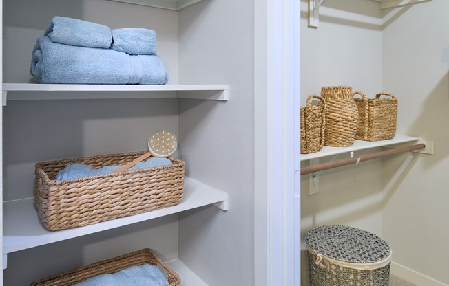 A white closet with baskets and towels.