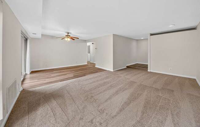 A room with a carpeted floor and a ceiling fan.
