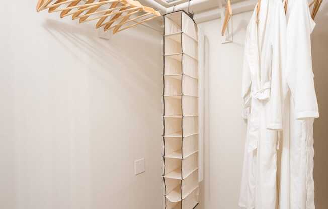 a walk in closet with white walls and wooden floors