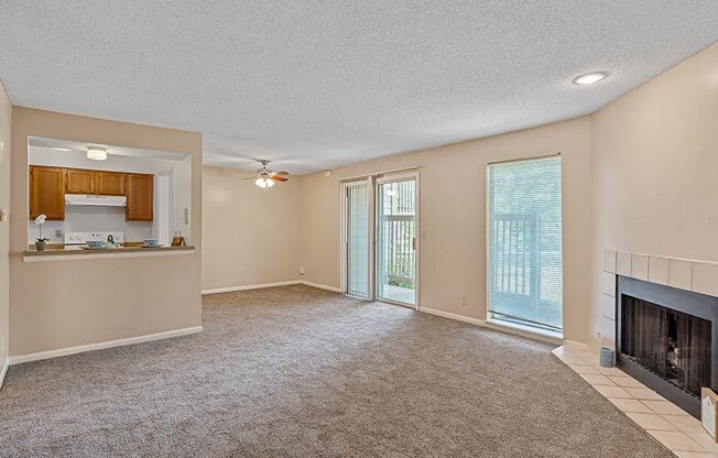 an empty living room with a fireplace and a kitchen