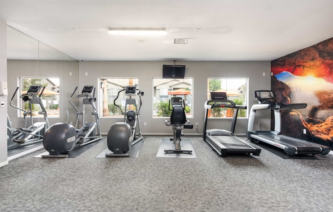 a gym with treadmills and other exercise equipment in a building with windows