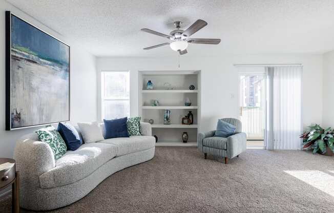 a living room with a couch and a chair and a ceiling fan