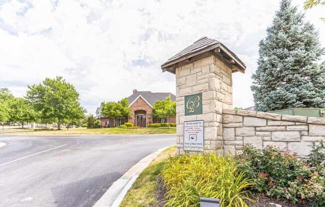 the front entrance of a house with a stone wall and a sign on the side