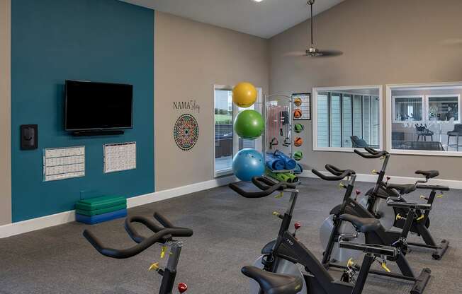 A gym with exercise equipment and a TV.