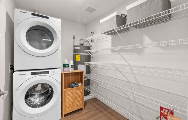 A white dryer is in a laundry room with a shelf and racks.