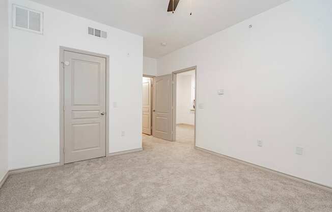 a bedroom with white walls and carpet and a door to a closet
