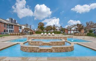 A large outdoor swimming pool with a hot tub in the middle.