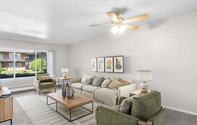 A living room with a ceiling fan and a large window.