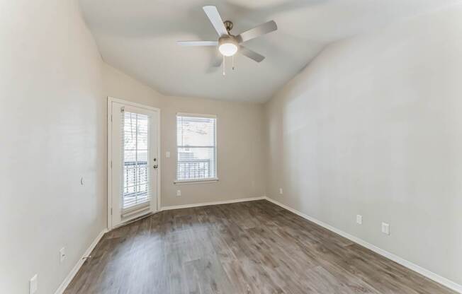 A room with a ceiling fan and wooden flooring.