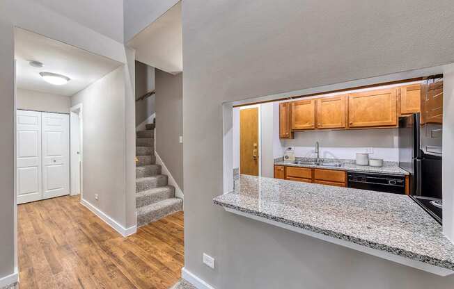 Room with a glimpse into the kitchen and carpeted staircase