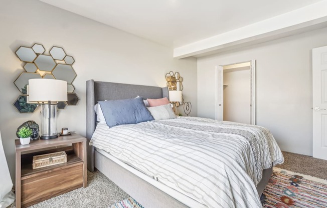 A bedroom with a bed, nightstand, and lamp.