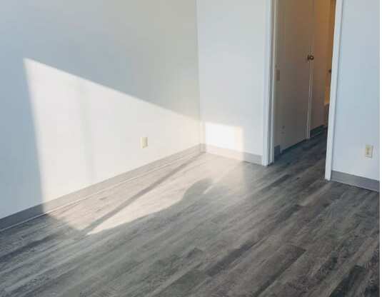 an empty room with white walls and wood floors