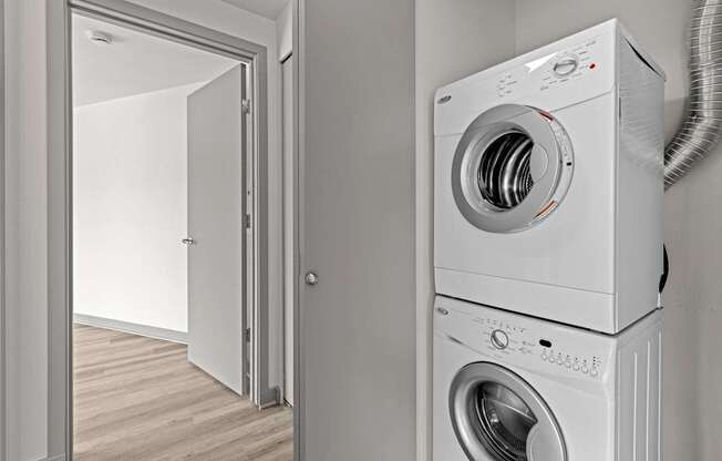 A white washing machine is stacked on top of another in a room.