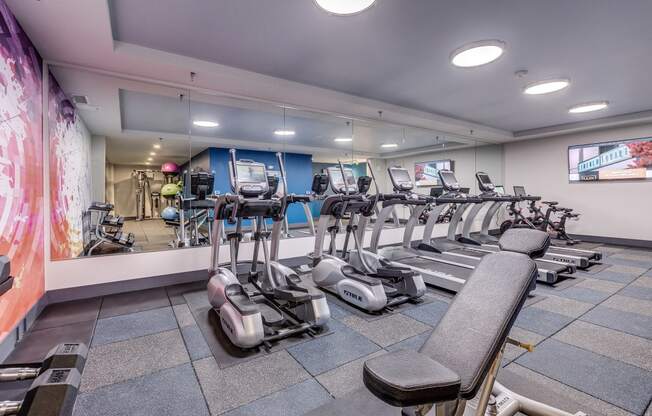 Lux Apartments Bellevue WA 24-hour fitness center amenity with ellipticals, treadmills, free weights, and strength training machines