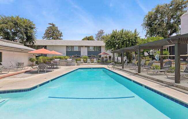 A large swimming pool with a blue tiled edge and a white building in the background.