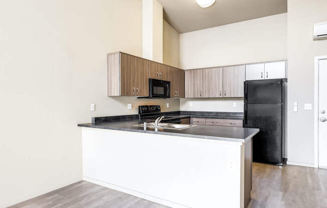 A kitchen with a black refrigerator and white countertops.