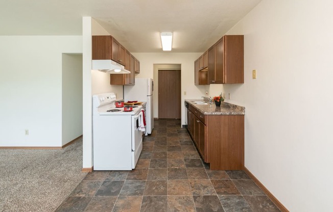 a kitchen with white appliances and wooden cabinets. Fargo, ND Islander Apartments