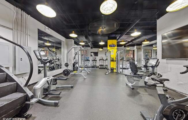 a gym with weights and cardio equipment on the floor and a wall mounted tv