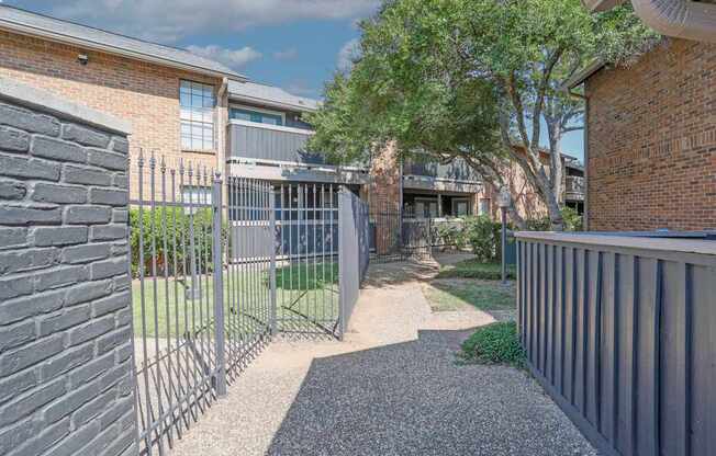 A gravel path leads to a gated entrance.