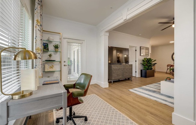 A room with a desk, chair, and a lamp.