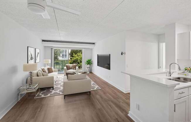 Model living room with a white kitchen area and a television.