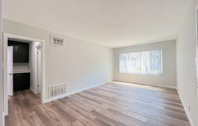 an empty living room with wood flooring and a window