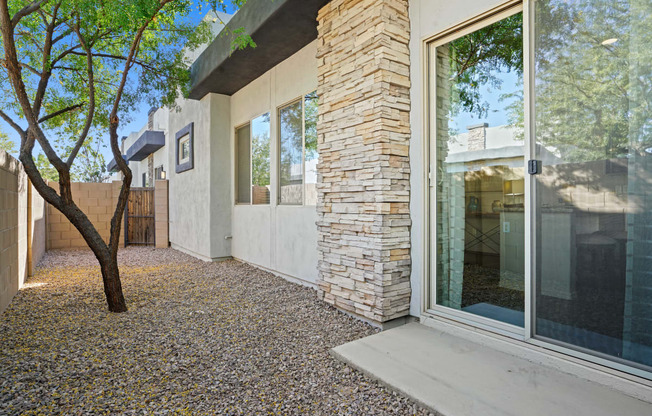 a patio with a tree and a white house with glass doors