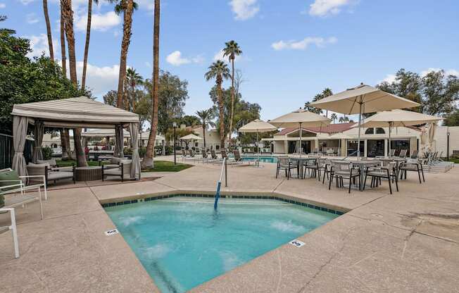 A pool area with a gazebo and lounge chairs.