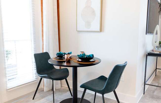 A dining table with two chairs and a bowl of blueberries on it.