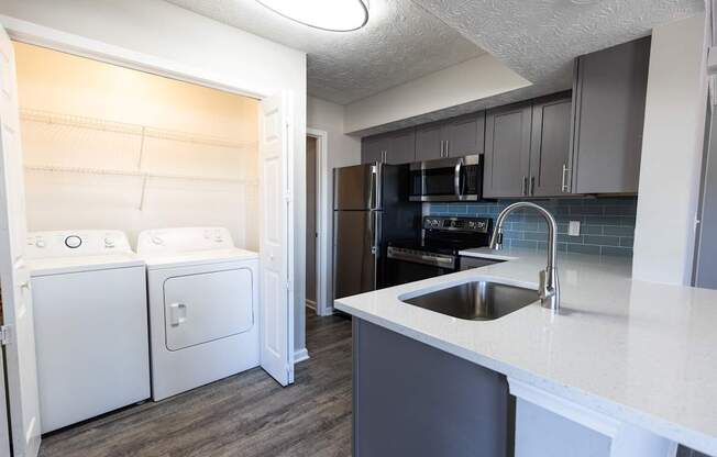 A kitchen with a white counter top and a black refrigerator.