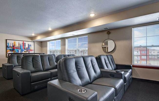 a theater room with leather couches and chairs