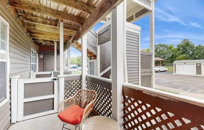 a covered porch with two chairs and a table