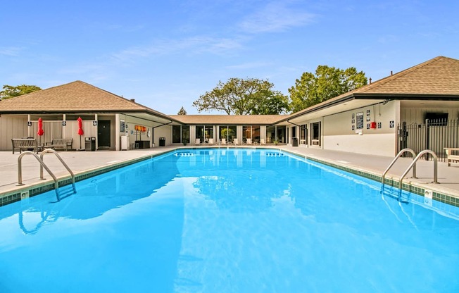 A large swimming pool in front of a building with a clear blue sky above.