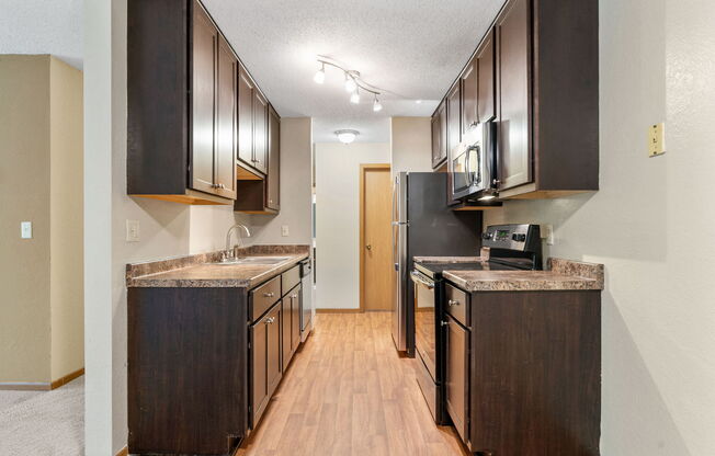a kitchen with dark cabinets and a stove and a refrigerator