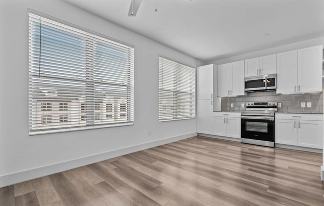 an empty kitchen with white cabinets and a large window